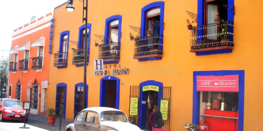 Vibrant colonial-style buildings in a colorful Mexican town with a vintage car and local shops.