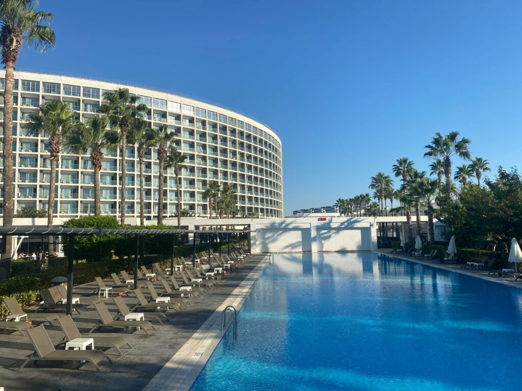 Sunny day at a luxurious resort with a large swimming pool and palm trees.