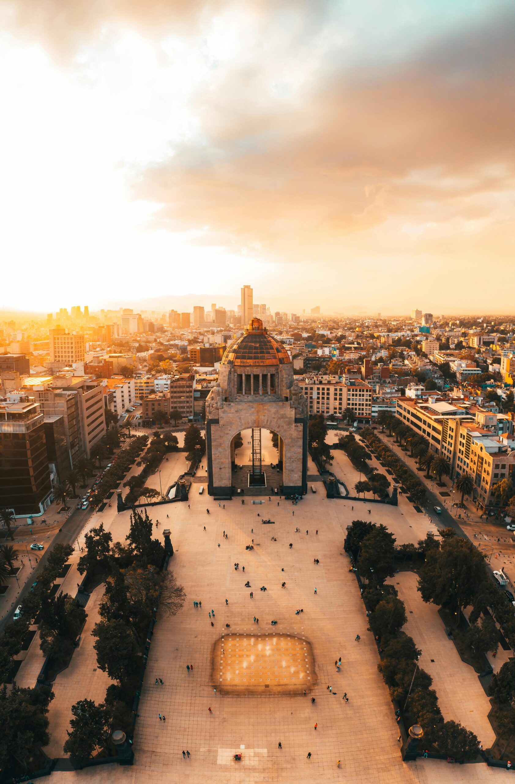 Aerial view of the iconic plaza monument during sunset in Mexico City, featuring rich architecture and busy streets.