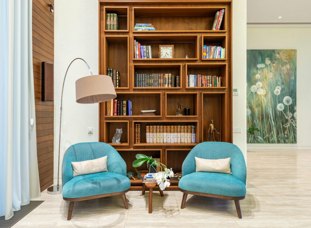 An inviting interior with a modern bookshelf complete with books and teal armchairs for cozy reading.