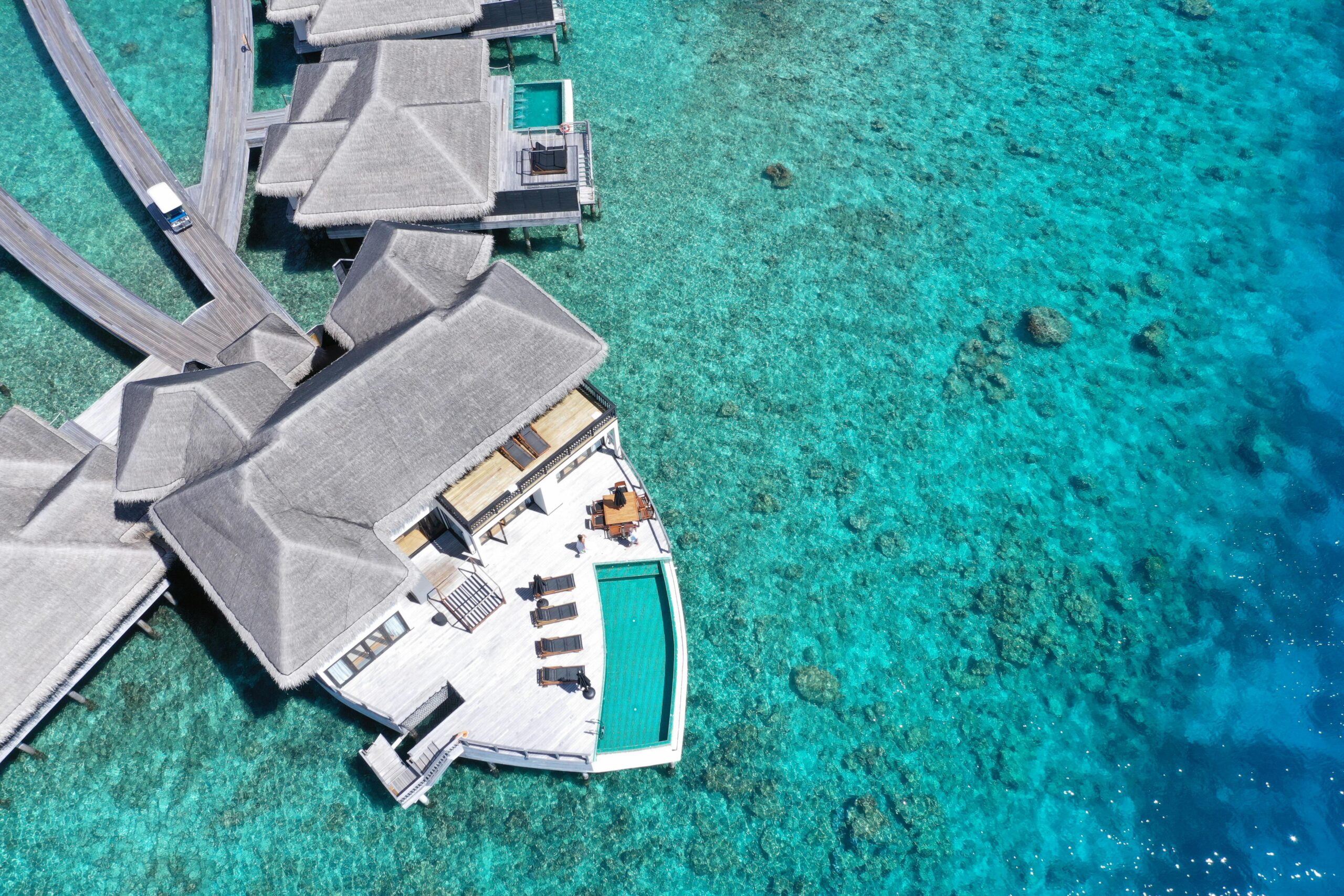 Aerial view of a luxurious overwater villa in Maldives, set amidst pristine turquoise waters.