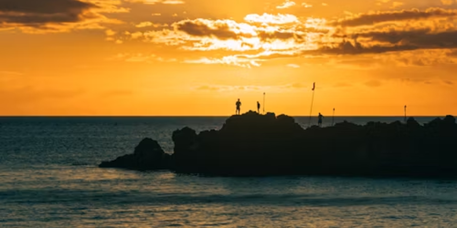 Scenic sunset over the ocean with silhouettes of people on rocky cliffs in Mexico